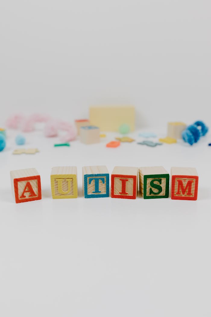 why-choose-us Colorful blocks spelling 'autism' with blurred toys in background.